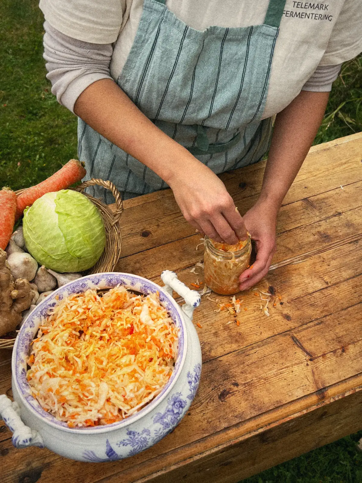 Kål pakkes i glass, sett ovenfra, ved siden av en terrin med kimchi